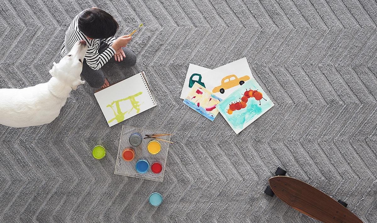 A boy painting with acrylics on a carpet rug, an accident waiting to happen